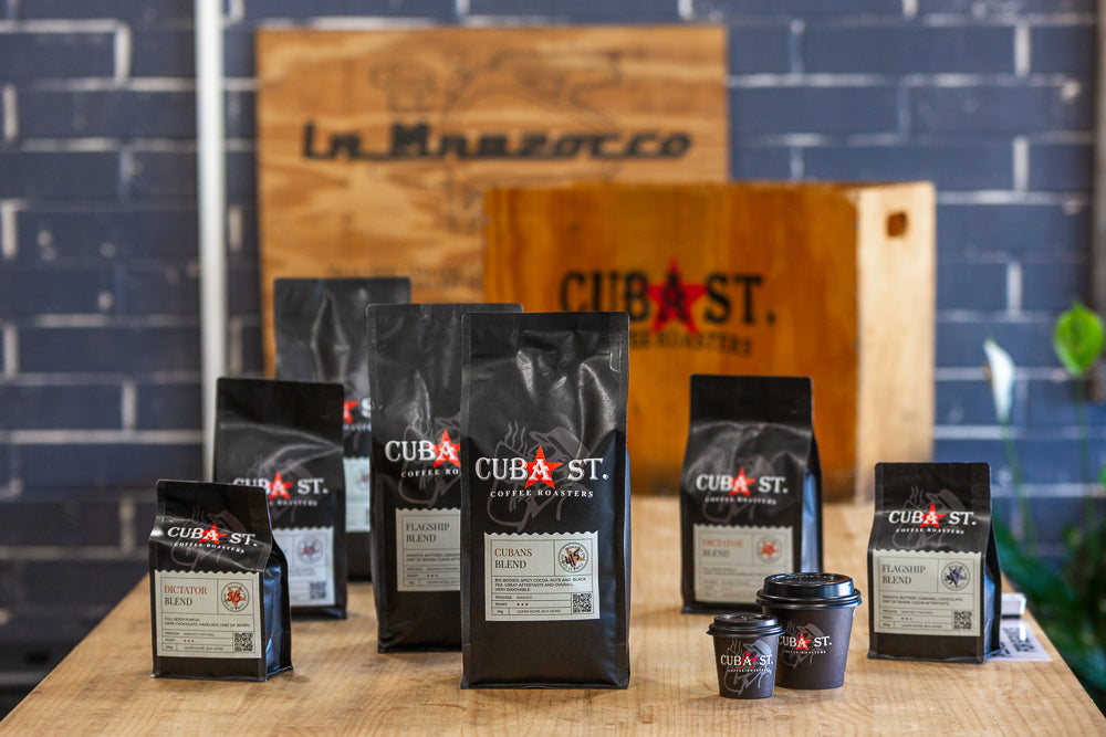Cuba St. coffee bags on a wooden surface with a brick wall background